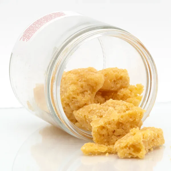 Jar filled with golden cannabis wax concentrate, showing a crumbly texture that represents an ounce of wax
